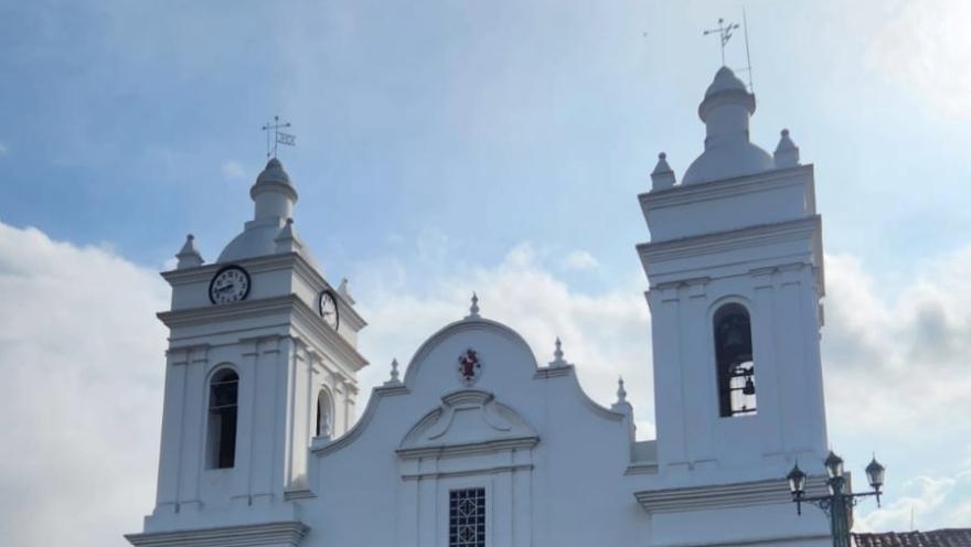 Primer plano de la parte alta de la fachada de la catedral en la que sobresalen las torres laterales con campanarios, en uno de ellos la torre del reloj.
