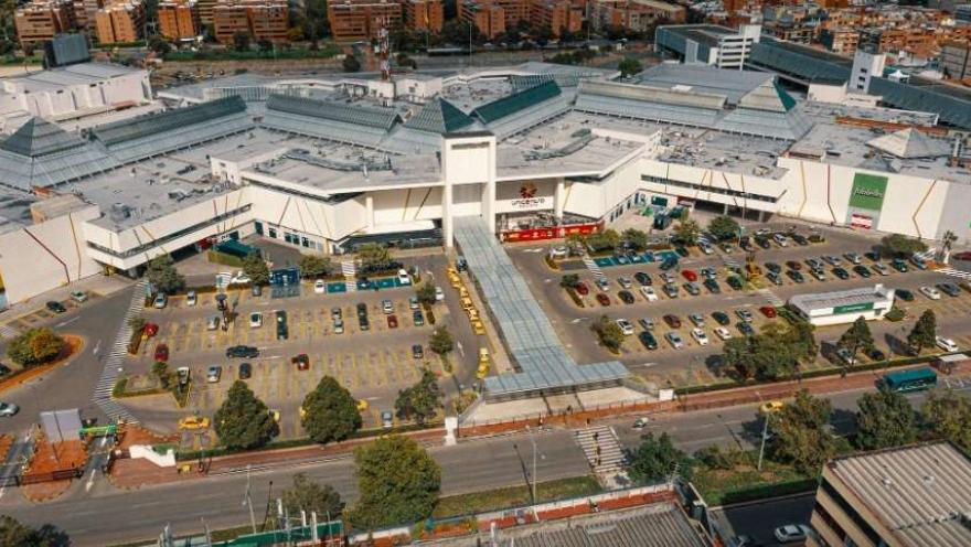 Plano general de lado de la fachada de una gran zona de edificaciones de mediana altura, con una amplia área de parqueaderos.