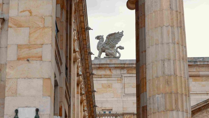 Se observa una figura mitológica alada en el techo de la edificación en piedra.
