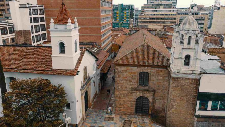 View from above of the church's facade and brick-tiled roof. Another church is visible next door, and buildings are visible in the background.