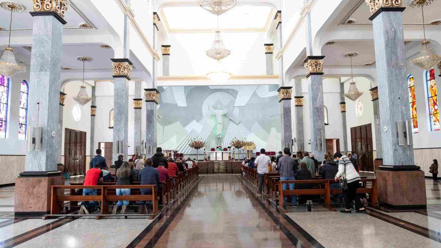  Plano general del interior de la iglesia donde hay personas de rodillas y de pie orando.