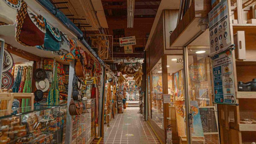 Interior de locales comerciales con coloridos artículos artesanales como sombreros, ruanas y hamacas.