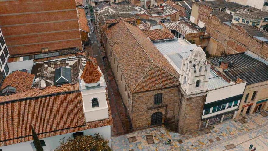 View from above of the church's facade and brick-tiled roof. Another church is visible next door.