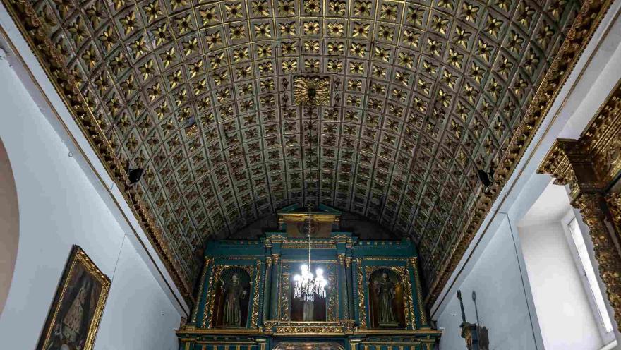  Interior de la iglesia en el que se observa un bello retablo de color verde en el frente y un dorado en el techo.