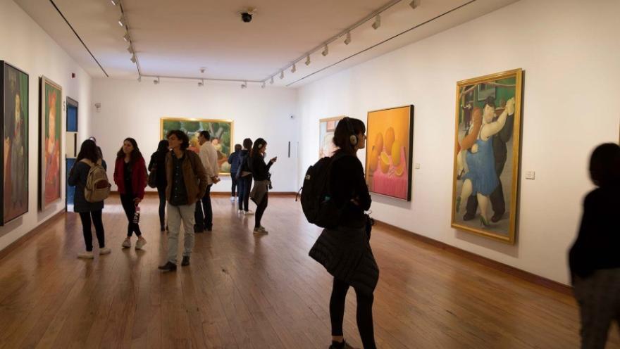 Interior de sala de exposición del Museo Botero en el que hay varias personas jóvenes observando algunos cuadros.