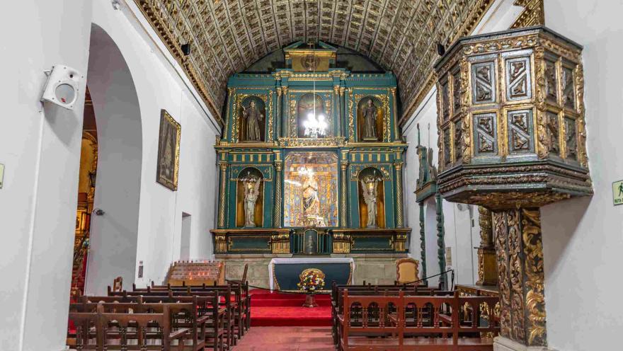 Capilla interior de la iglesia en la que se destacan el altar y el púlpito en madera tallada.