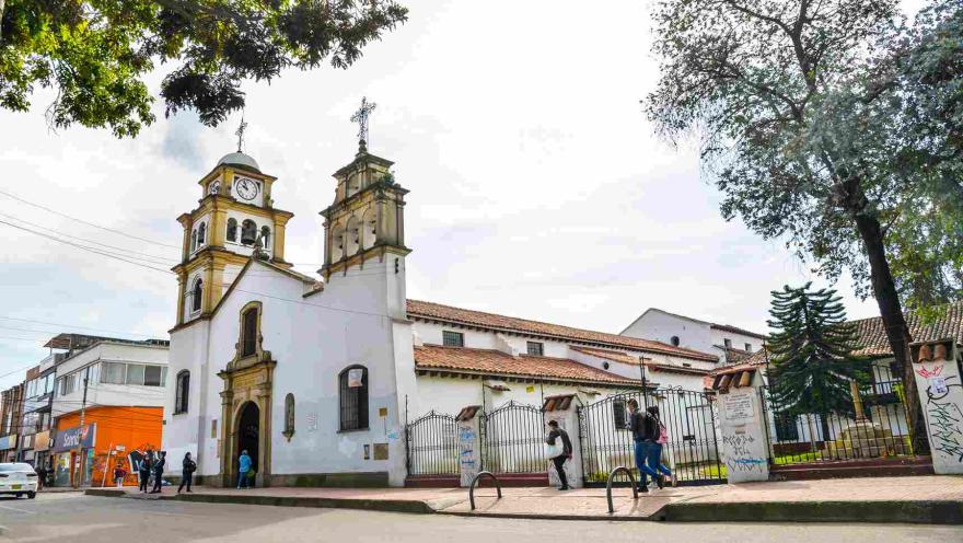 Plano de la iglesia vista desde un lado, en la que sobresalen sus dos torres y varias personas al frente.