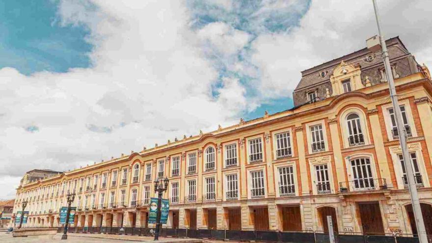 Primer plano de plano general de la fachada exterior del palacio, vista de frente. Hay tres juegos de faroles metálicos al frente.