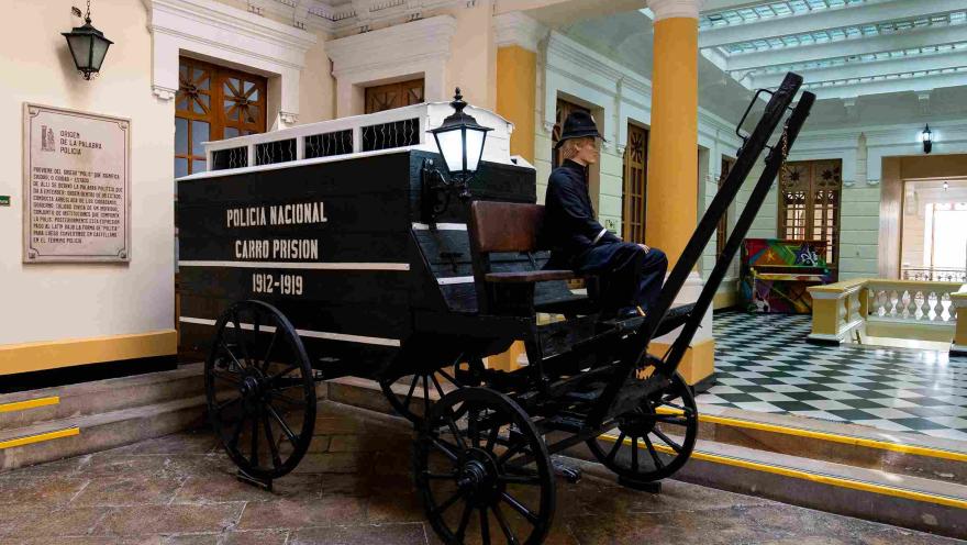  Carruaje negro en el que hay un maniquí de conductor y una leyenda que indica para qué funcionaba y que dice: “Policía Nacional - Carro prisión, 1912-1919”.