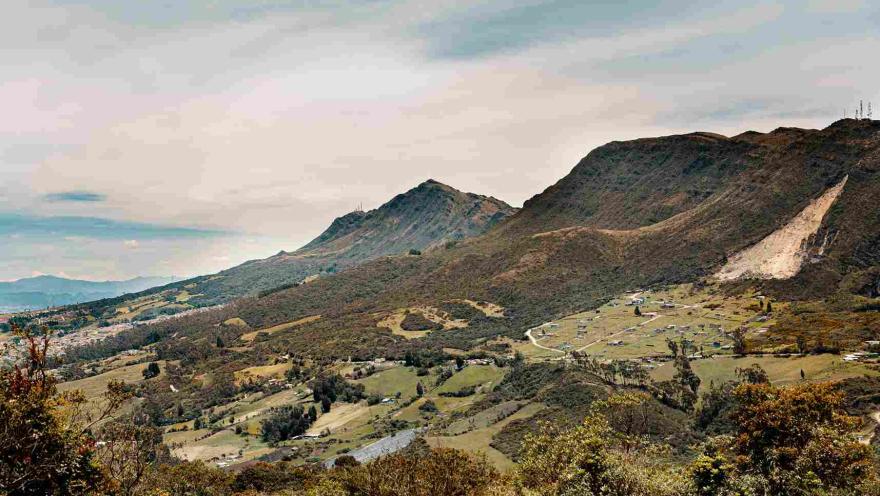 Vista de un valle rodeado de montañas, con un pequeño pueblo al fondo.