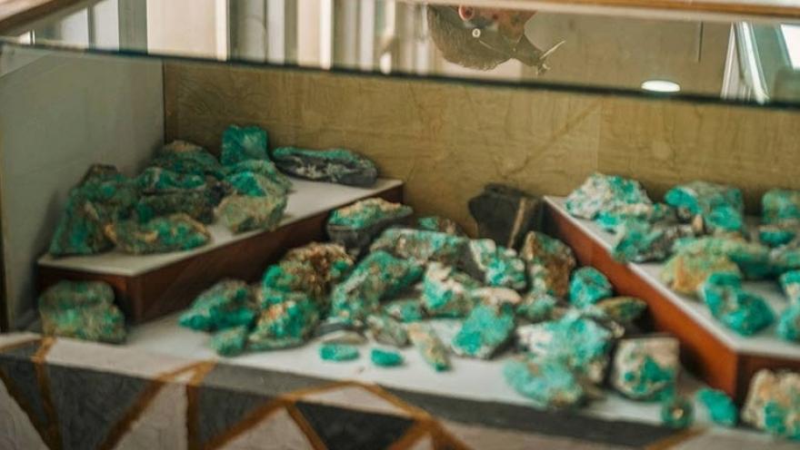  Vitrina de museo con varias esmeraldas en bruto de color verde intenso expuestas sobre soportes blancos. Las piedras de diferentes tamaños y formas están protegidas por un vidrio y exhibidas como parte de una colección mineral.