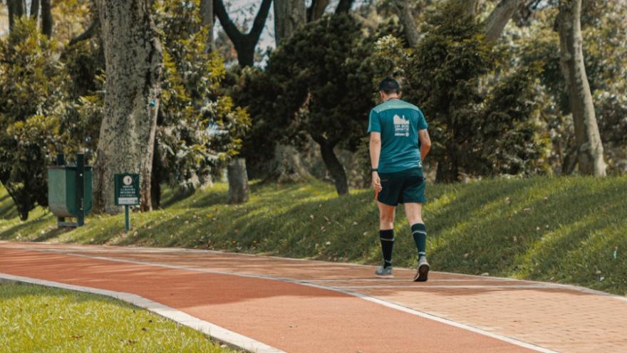 Hombre caminando por un sendero. Como va en pantaloneta y tenis parece que hace ejercicio.