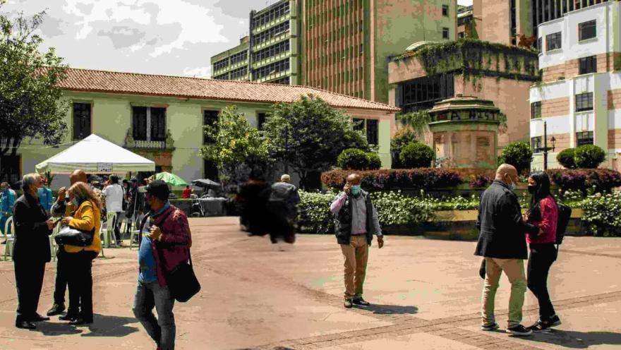 People standing in a patio with buildings in the background, enjoying the atmosphere and conversing.