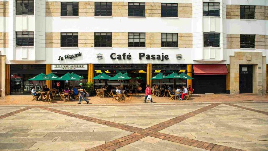 A café in a plaza with tables and chairs outside, ready for customers to enjoy their drinks outdoors.
