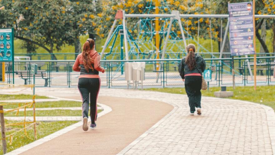 Dos mujeres corren juntas en un parque, disfrutando del aire libre y la actividad física.