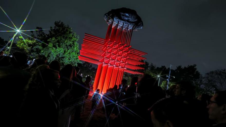  Una gran cruz roja iluminada en la noche, destacando en el cielo oscuro.