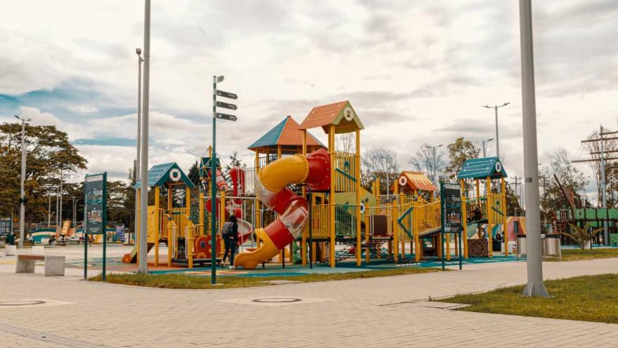  Un parque infantil con un tobogán colorido y un conjunto de juegos para niños.    