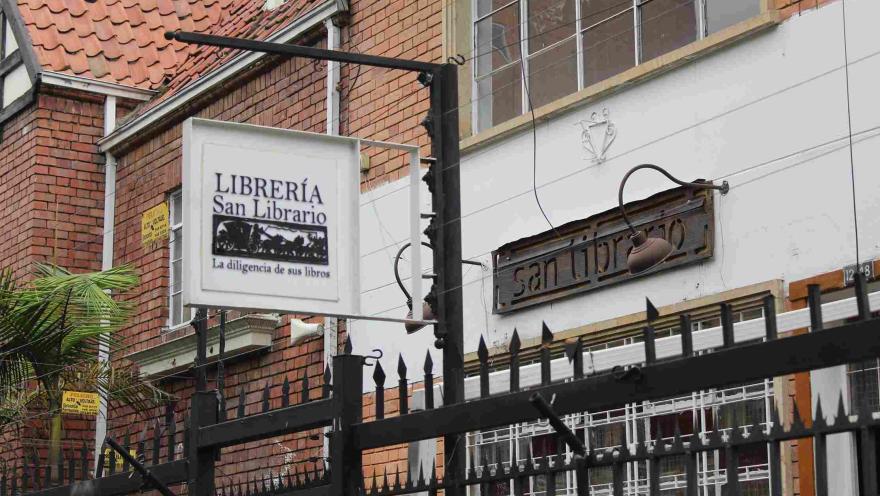 Fachada de la librería San Librario con letrero colgante en una calle de ladrillo.