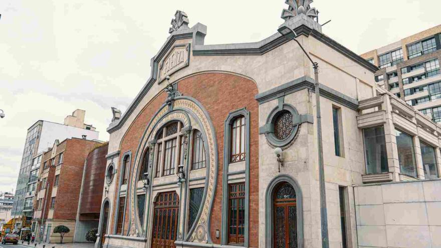 La imagen muestra un edificio de estilo arquitectónico clásico con detalles ornamentales, donde se combinan muros de ladrillo y piedra clara. Su fachada destaca por arcos decorativos y elementos artísticos en la parte superior, evocando un carácter cultural e histórico.