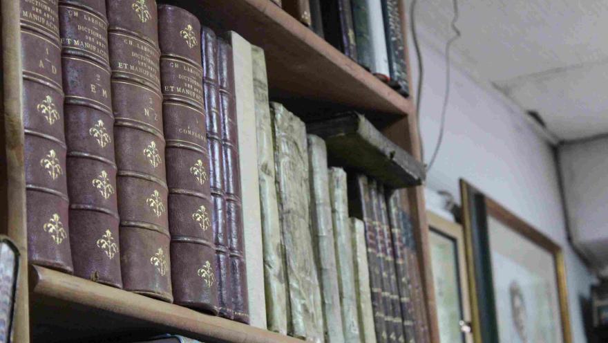 Primer plano de libros antiguos encuadernados en cuero sobre una estantería de madera.