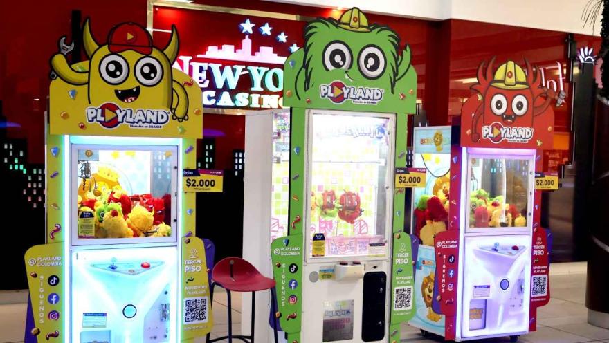 Máquinas de juego tipo garra con peluches en un centro comercial, decoradas con personajes coloridos de Playland.