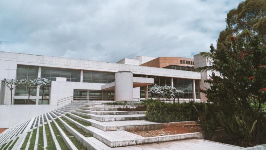Edificio cultural moderno con escalinatas amplias, ventanales y jardines bajo un cielo nublado.