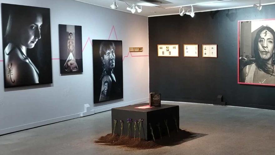  Sala de museo con exposición de retratos fotográficos y una instalación central en el piso.
