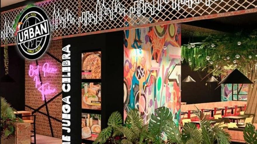 Fachada de un local “URBAN” con diseño moderno, grafitis coloridos, iluminación neón y vista al interior con mesas y decoración tropical.