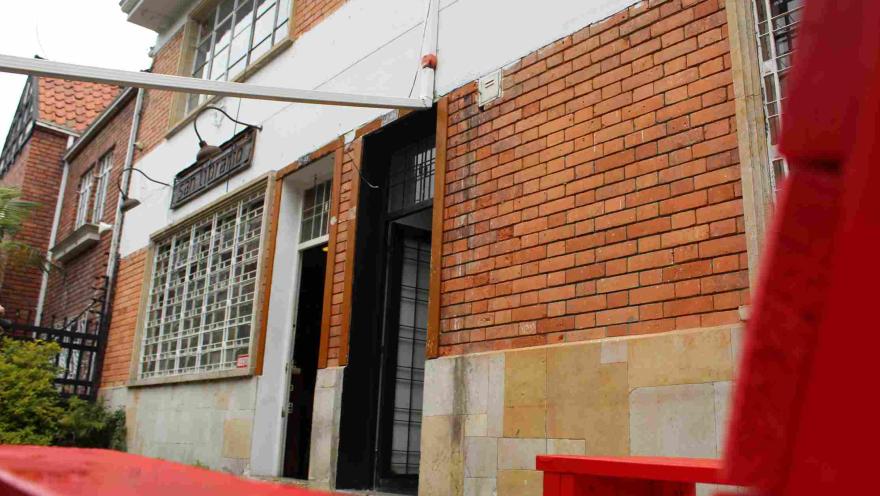 Entrada de la librería San Librario en fachada de ladrillo, con banca roja en primer plano.