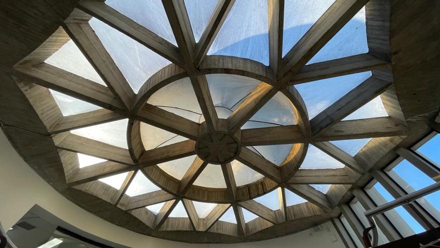 Cúpula de vidrio y concreto con diseño geométrico que deja entrar luz natural en un espacio interior.