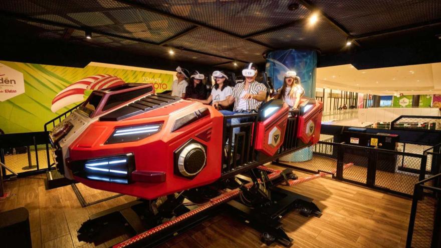Grupo de personas usa gafas de realidad virtual en un simulador de movimiento con forma de vehículo futurista dentro de un espacio recreativo interior.
