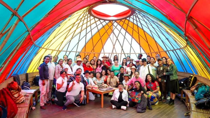  Grupo de personas reunidas dentro de un domo colorido participando en un encuentro comunitario.