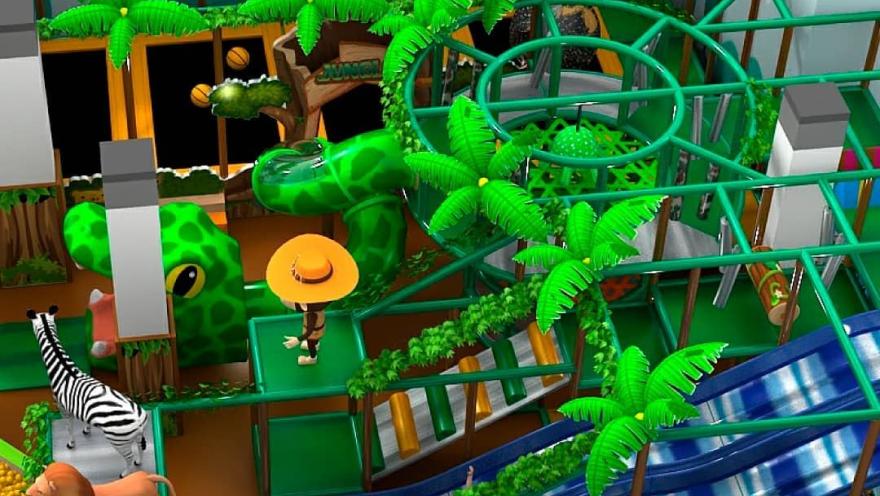 Zona de juegos infantil temática de selva con toboganes, estructuras verdes, palmeras decorativas y figuras de animales como león, cebra y serpiente.