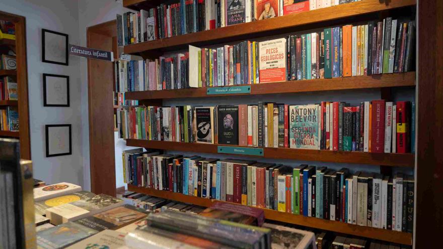 Wooden bookshelf full of books organized by category, with history and literature titles in a bookstore.