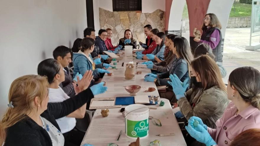 Un grupo de personas sentadas a una mesa, todas usando guantes, conversando y compartiendo ideas.