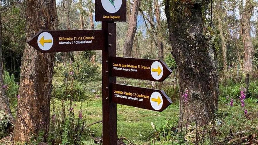 Tourist signage in a Bogotá forest indicating ecological routes and trails to different natural sites.