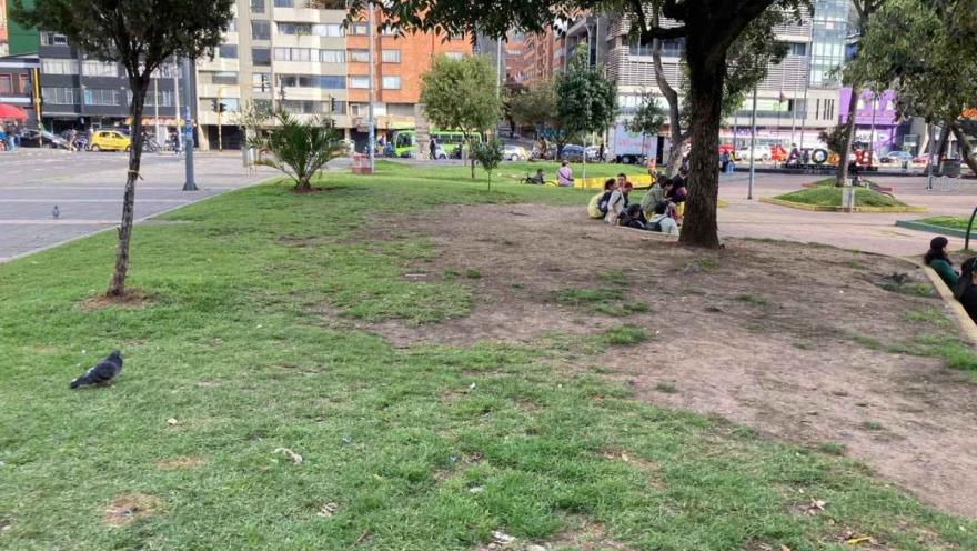 Zona verde urbana con árboles y personas descansando en un parque de Bogotá, rodeado de edificios y vías de la ciudad.