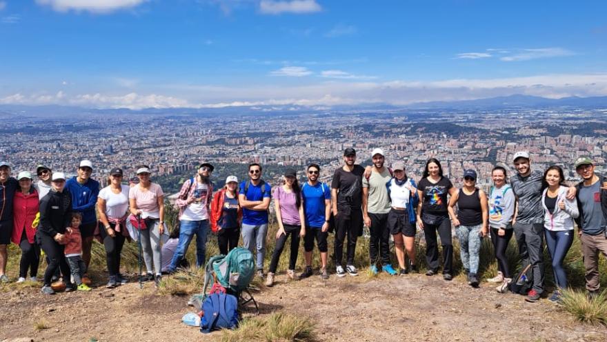 Group of people posing at a natural viewpoint with a panoramic view of Bogotá and the mountains in the background.