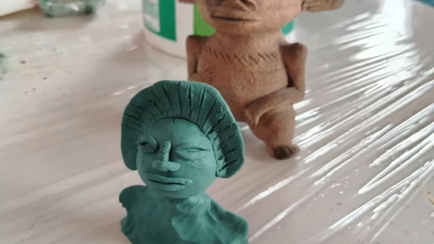  Escultura de arcilla que representa a una mujer y un hombre en una pose íntima y expresiva.