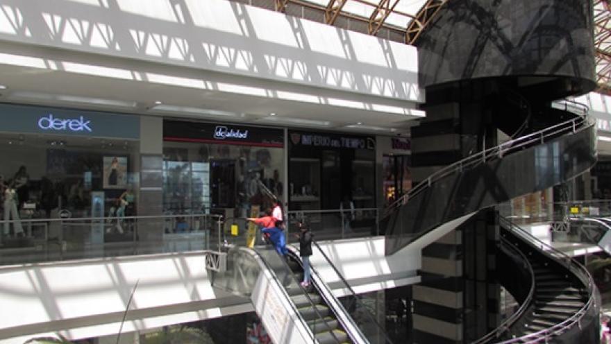 Interior del centro comercial Gran Estación con escaleras eléctricas, locales comerciales y una estructura moderna iluminada por luz natural.
