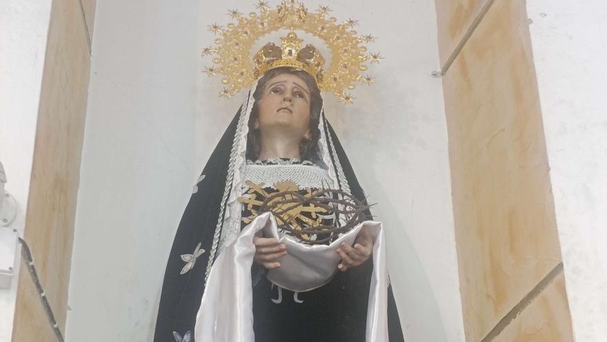 Primer plano de la Virgen de los Dolores con corona dorada, sosteniendo una corona de espinas, ubicada en un nicho de iglesia.