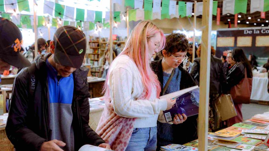 Visitantes recorren y exploran libros en un stand de feria literaria, en un ambiente cultural lleno de lectores, editoriales y actividades alrededor de la literatura.