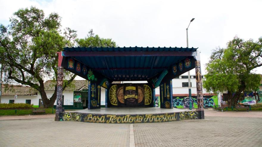 Escenario cubierto en la plaza de Bosa con murales coloridos y la frase “Bosa territorio ancestral”.