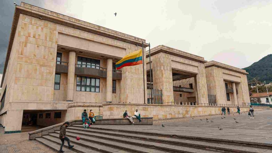 De lado, fachada de estructura con tres edificaciones en piedra. Sobresale al frente izada una bandera de Colombia.