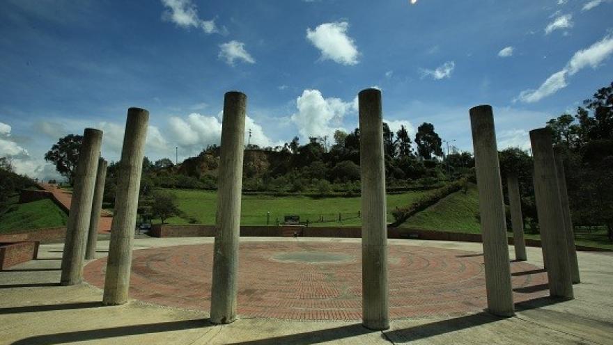 Un círculo de columnas se alza en medio del Parque Mirador de los Nevados, creando un espacio abierto para el encuentro y la contemplación del paisaje natural bajo el cielo azul de Bogotá.