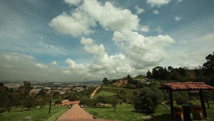Desde lo alto del Parque Mirador de los Nevados se aprecia un amplio paisaje verde que desciende hacia la ciudad, enmarcado por senderos naturales y un cielo lleno de nubes que resalta la tranquilidad del lugar.