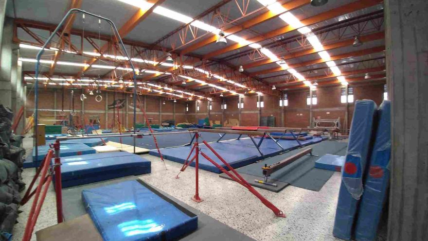  Sala de gimnasia del Coliseo Cayetano Cañizares equipada con barras, anillos, vigas de equilibrio, colchonetas y áreas de entrenamiento especializadas, diseñada para la práctica y formación de atletas en distintas disciplinas gimnásticas.