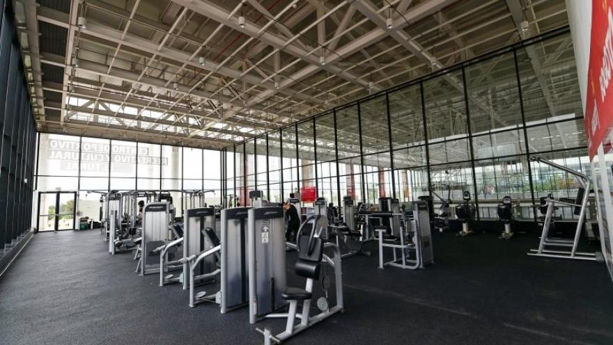  Interior del gimnasio del Centro Felicidad (CEFE) El Tunal, equipado con modernas máquinas de entrenamiento y amplios espacios para la actividad física. La iluminación natural, las fachadas en vidrio y el diseño abierto crean un ambiente cómodo y funcional para el ejercicio y el bienestar de los visitantes.