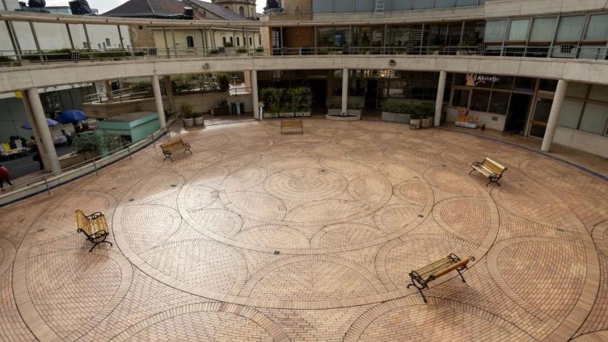 Plazoleta México del Centro Cultural Gabriel García Márquez en Bogotá, un amplio espacio abierto con pisos de ladrillo dispuestos en patrones circulares y bancas distribuidas alrededor. La plaza está rodeada por corredores y edificios de ladrillo diseñados por Rogelio Salmona, con vistas al entorno histórico de La Candelaria.