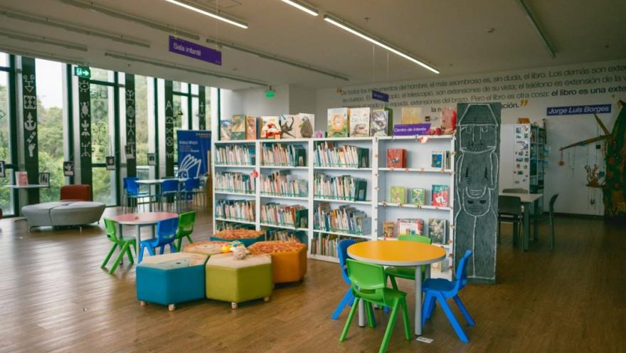 Sala infantil de la biblioteca del Centro Felicidad Cometas, equipada con estanterías de libros, mesas y sillas de colores, diseñada para fomentar la lectura, el aprendizaje y la creatividad de niños y niñas en un ambiente acogedor y moderno.